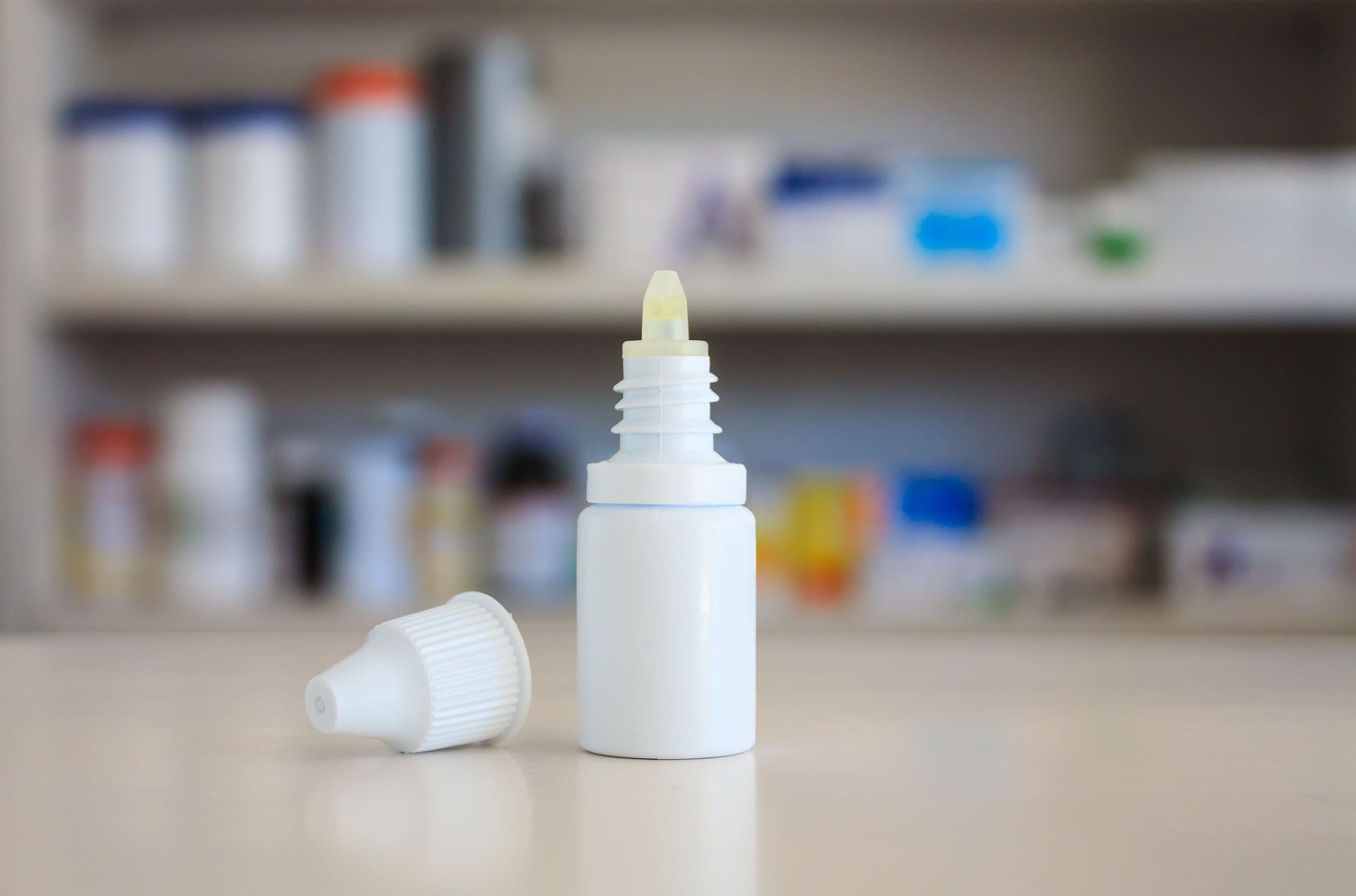 Eye drops medicine bottle with pharmacy store shelves background | Image Credit: © Kwangmoozaa - stock.adobe.com.