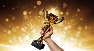 Man holding up a gold trophy cup | Image Credit: © Jag_cz - stock.adobe.com.