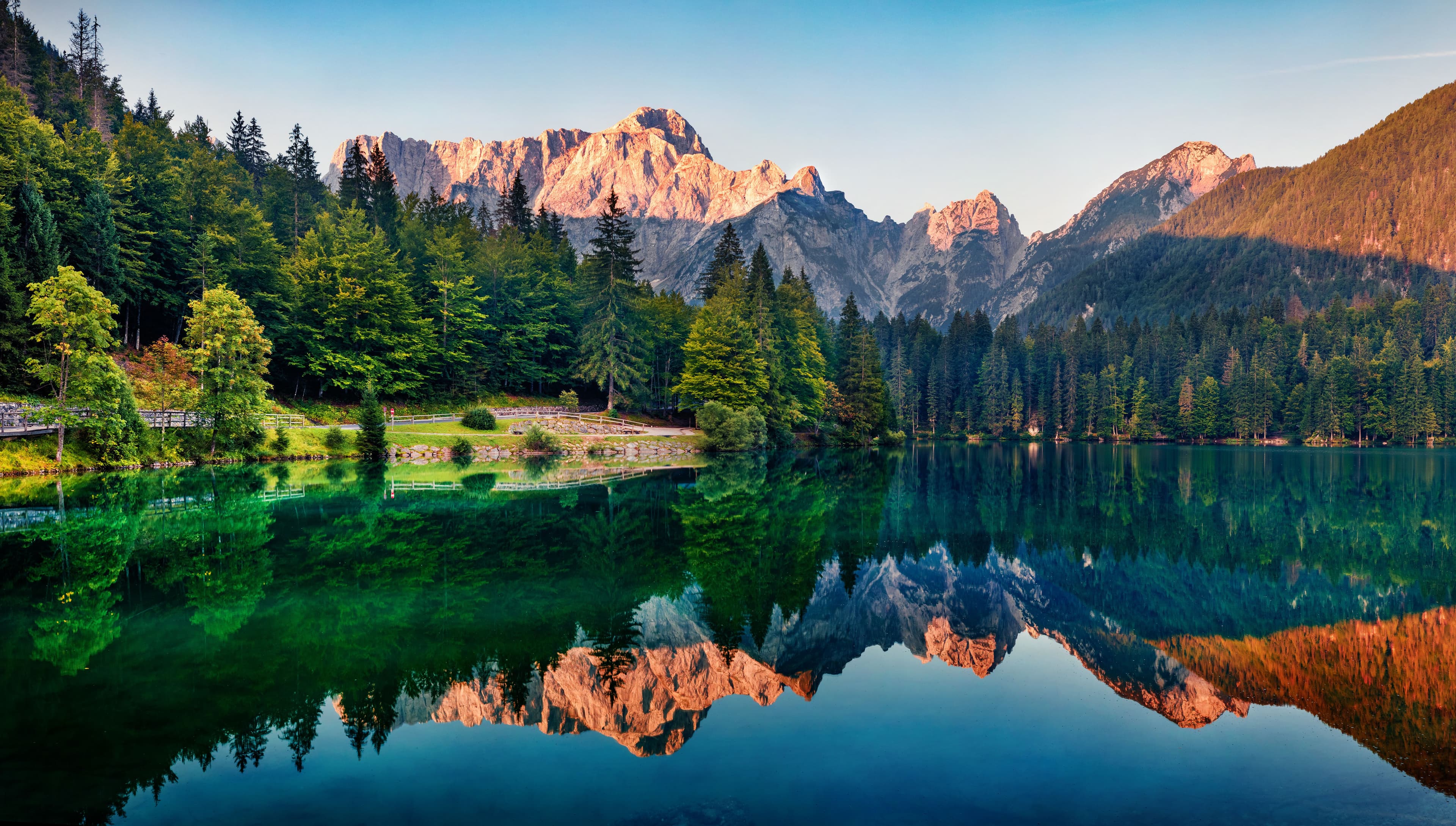 Calm morning view of Fusine lake. Colorful summer sunrise in Julian Alps with Mangart peak on background, Province of Udine, Italy, Europe. Beauty of nature concept background. | Image Credit: © Andrew Mayovskyy - stock.adobe.com