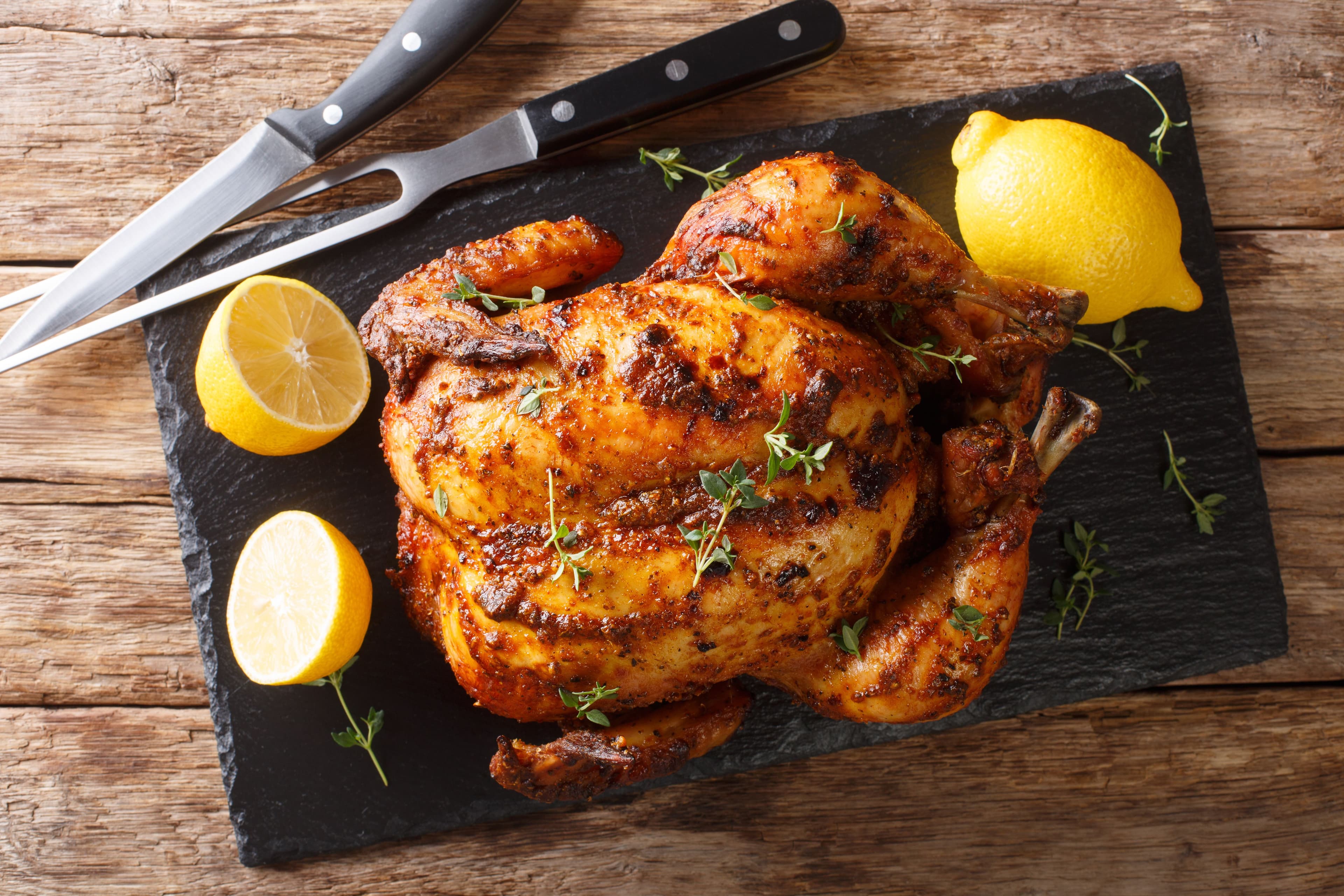 Homemade chicken rotisserie with thyme, lemon closeup on a slate board. Horizontal top view. | Image Credit: © FomaA - stock.adobe.com