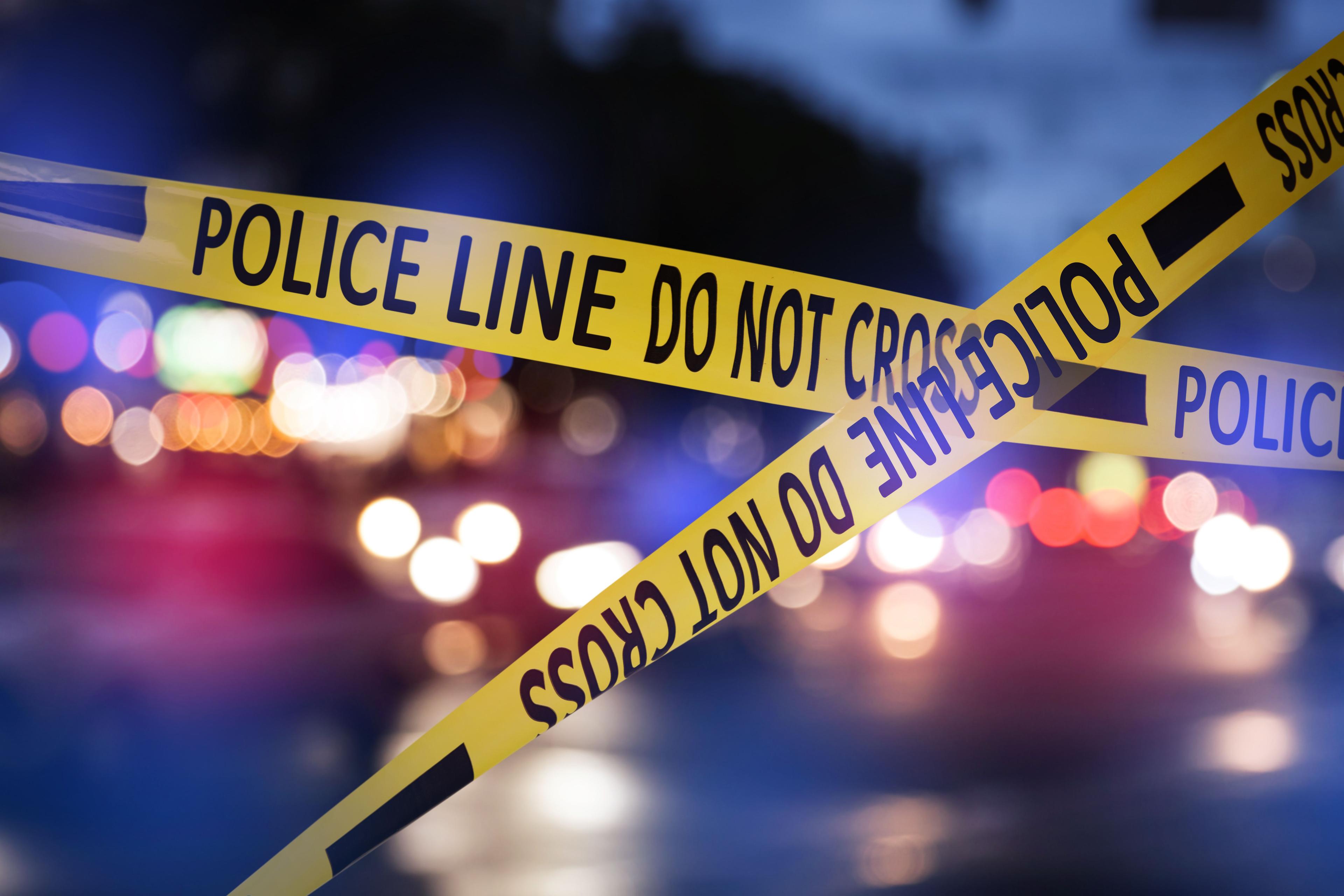 Yellow law enforcement tape isolating crime scene. Blurred view of city street, toned in red and blue police car lights | Image Credit: © New Africa - stock.adobe.com